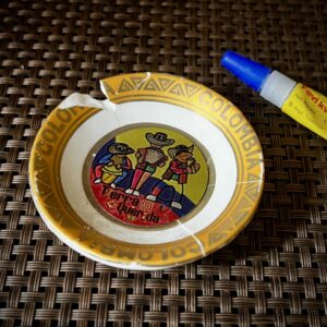 A small, repaired Colombian souvenir dish with visible cracks, glued back together using Fevikwik—illustrating the quiet, patient process of rewriting a story with care.