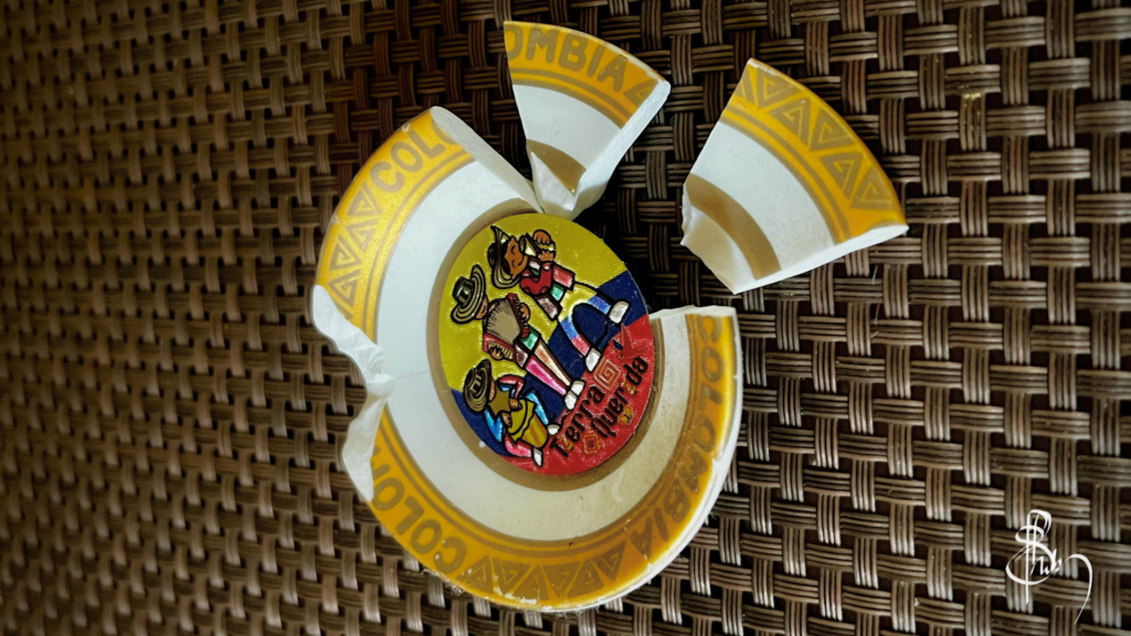 A broken ceramic souvenir from Colombia, its colorful pieces scattered on a woven mat—capturing a quiet metaphor for rewriting a story with care, where small fragments are patiently mended to form something meaningful again.